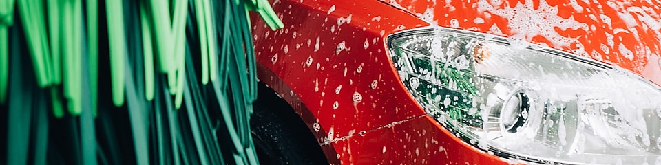 En röd bil tvättas i en Shell biltvätt