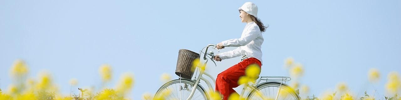 A young woman rides a bicycle through a flowery, summer field