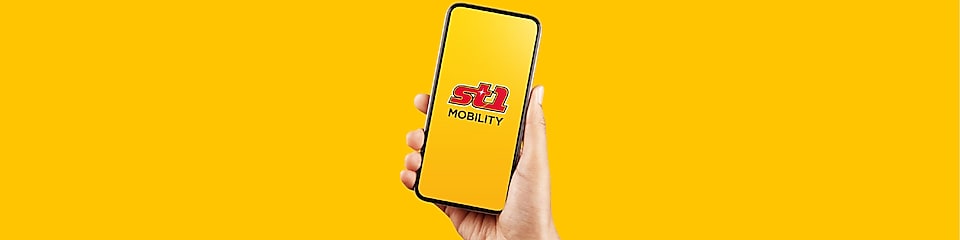 En hand håller en mobiltelefon där St1 logon och ordet Mobilty visas i skärmen