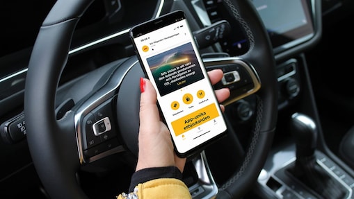 Hand håller en mobiltelefon. St1 Mobility appen visas i skärmen