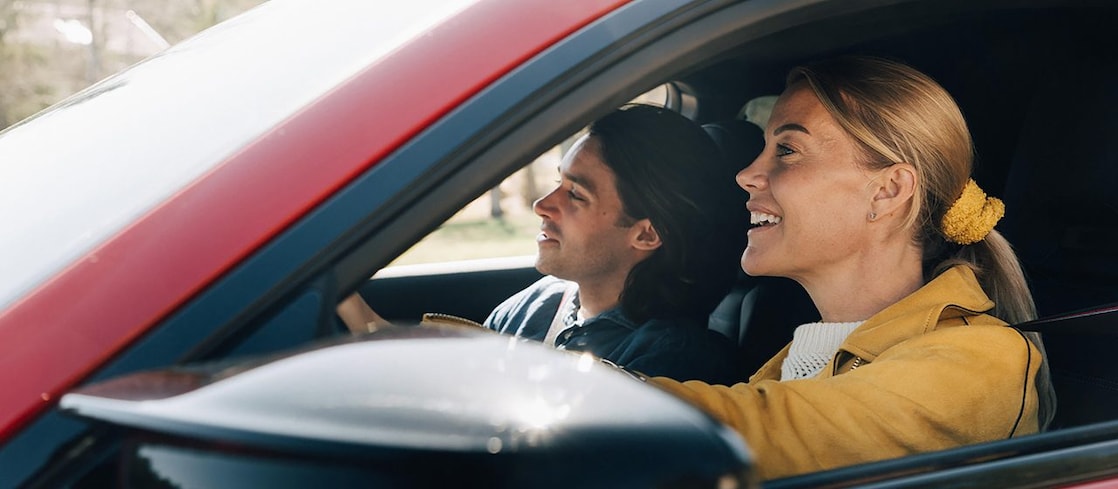 En man och en kvinna i en röd bil.