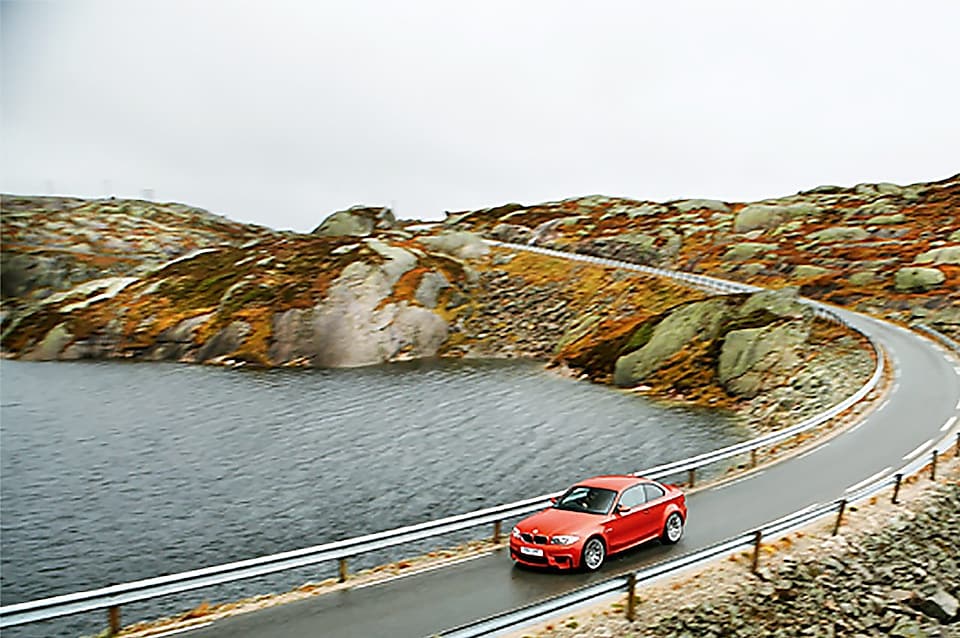 Rödfärgad bil på en väg nära vattnet