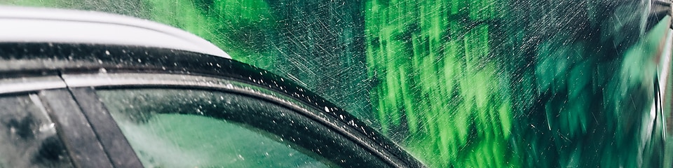 Svart bil och gröna tvättborstar i biltvätt på Shell