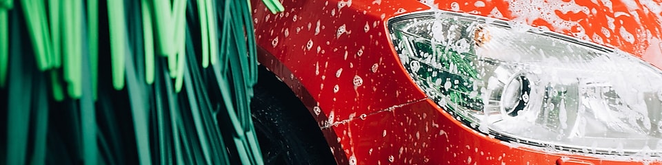Röd bil med tvättskum i en biltvätt vid Shell.
